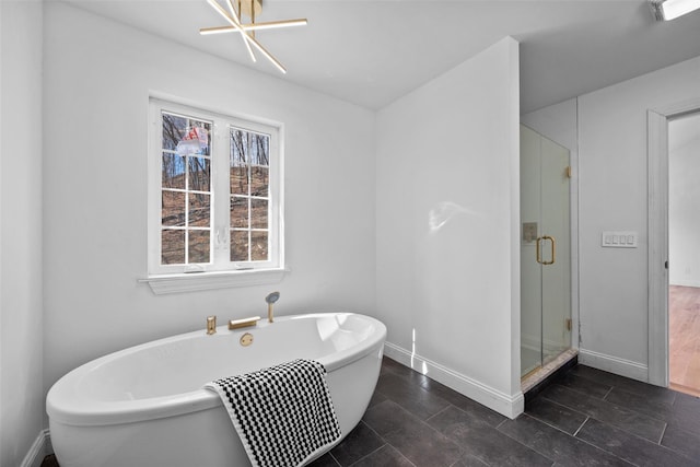 bathroom featuring a freestanding bath, a shower stall, and baseboards