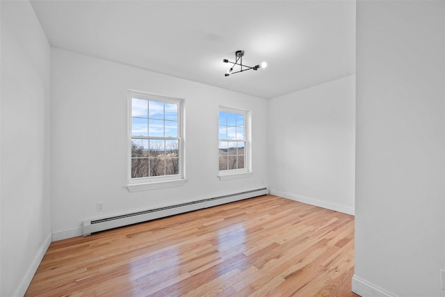 empty room with a baseboard heating unit, a chandelier, wood finished floors, and baseboards