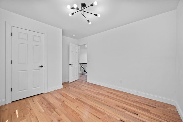 interior space with baseboards, light wood finished floors, and an inviting chandelier