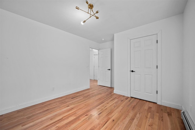 unfurnished bedroom with light wood finished floors, a baseboard radiator, baseboards, and a chandelier