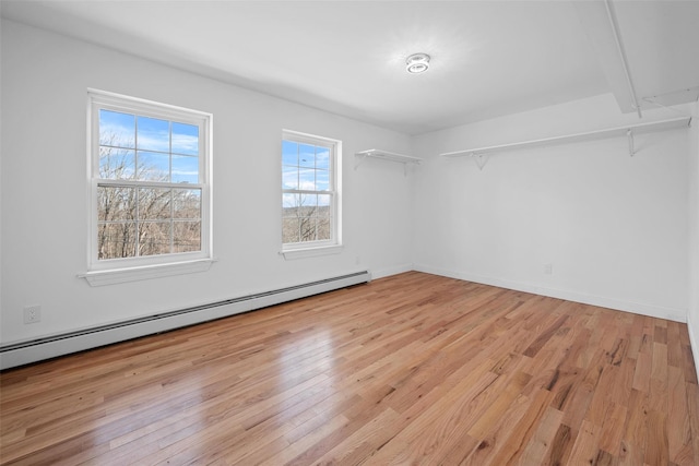 unfurnished room with light wood finished floors, baseboard heating, and baseboards