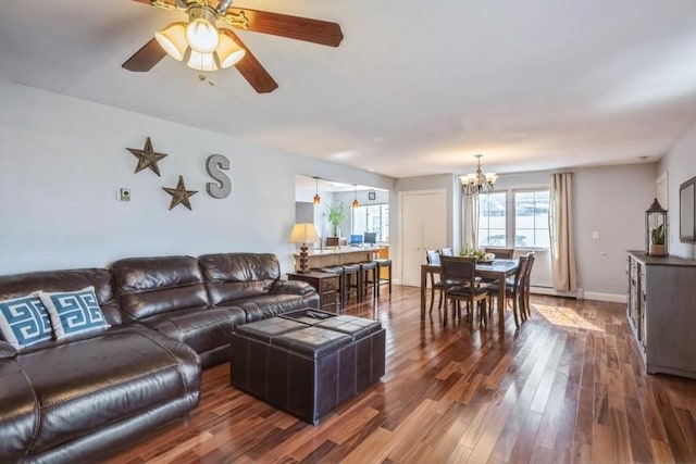 living area featuring dark wood-style floors, ceiling fan with notable chandelier, and baseboards