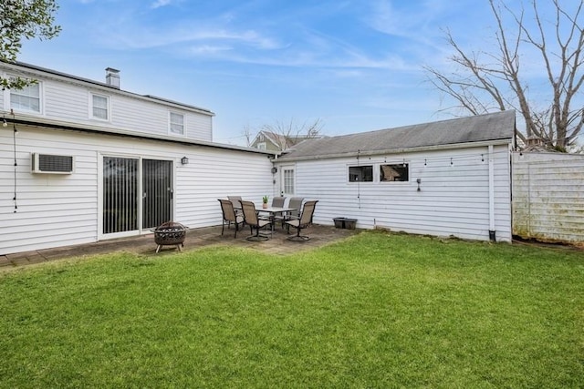 back of property with a lawn, a fire pit, and a patio