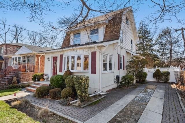 dutch colonial with fence and a gambrel roof