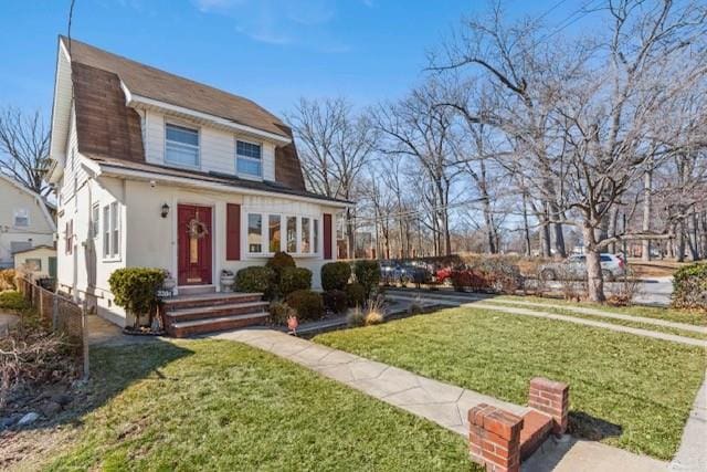 colonial inspired home with a front lawn, fence, and a gambrel roof