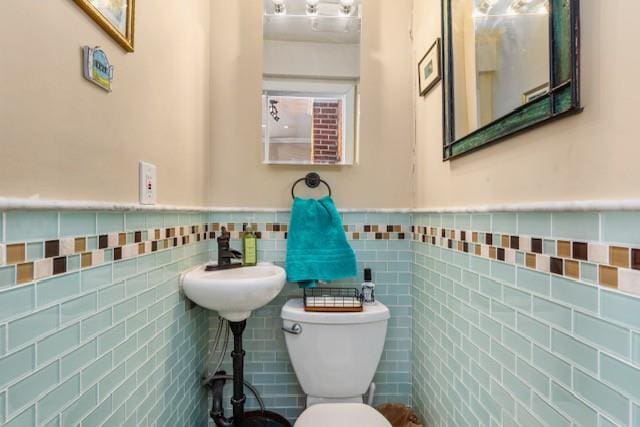 half bath featuring toilet, tile walls, and wainscoting