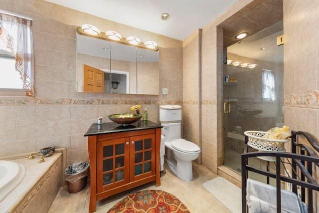 full bathroom featuring a relaxing tiled tub, tile walls, toilet, a shower stall, and tile patterned flooring