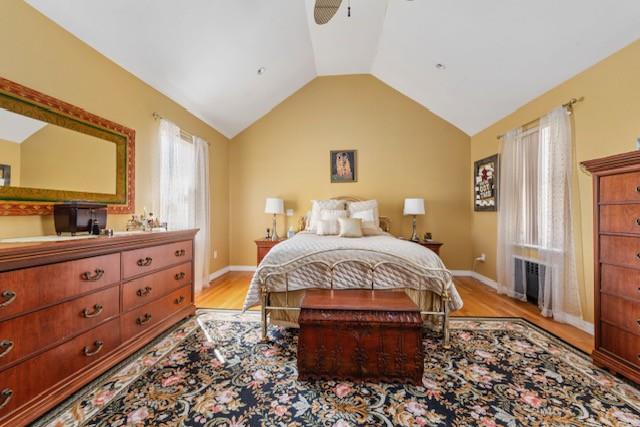 bedroom featuring lofted ceiling, ceiling fan, light wood-style flooring, and baseboards