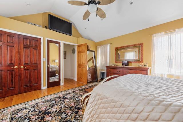 bedroom with ceiling fan, vaulted ceiling, and wood finished floors