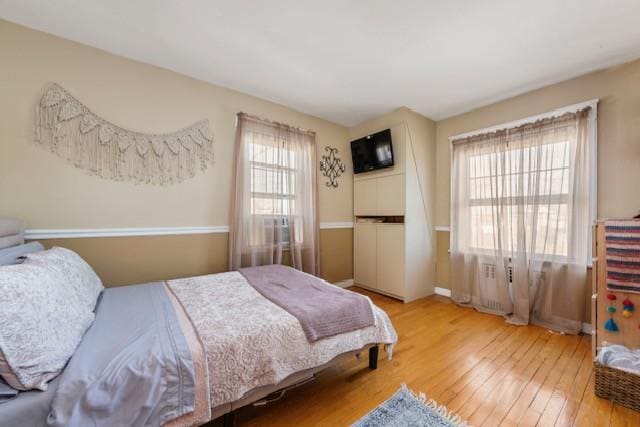 bedroom with radiator, baseboards, and hardwood / wood-style flooring