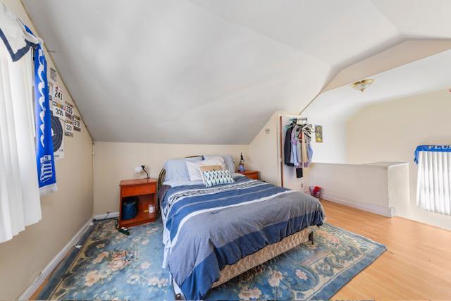 bedroom with lofted ceiling, baseboards, and wood finished floors