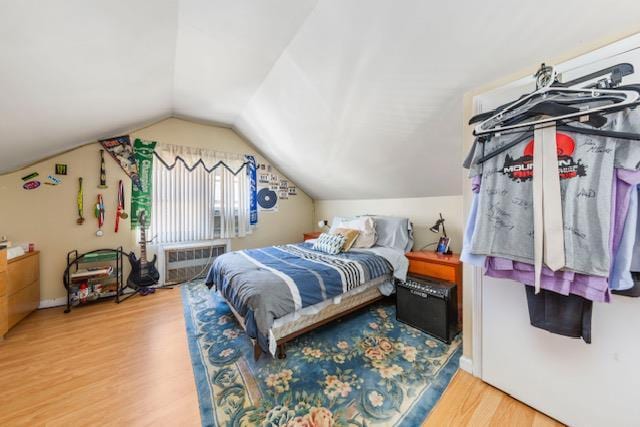 bedroom with vaulted ceiling, a wall mounted AC, and wood finished floors