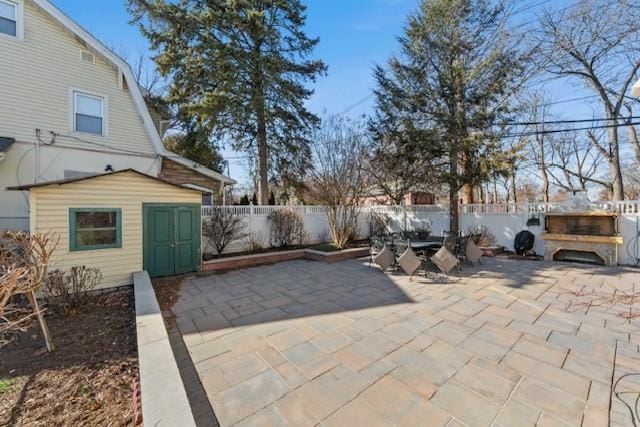 view of patio featuring an outbuilding, a fenced backyard, and outdoor dining space