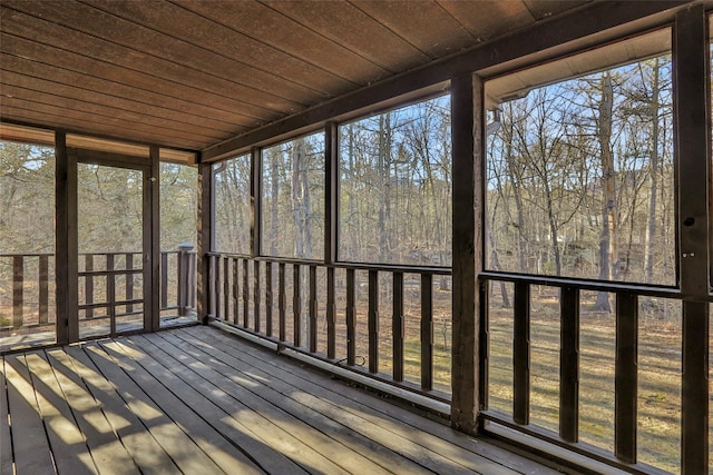 unfurnished sunroom with wood ceiling, a healthy amount of sunlight, and a forest view