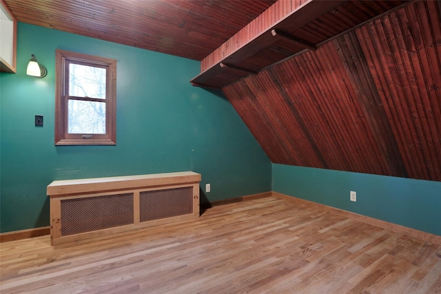 additional living space with radiator, wooden ceiling, baseboards, and wood finished floors