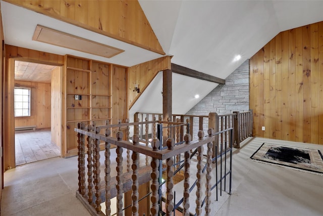 corridor with vaulted ceiling, baseboard heating, an upstairs landing, and wooden walls