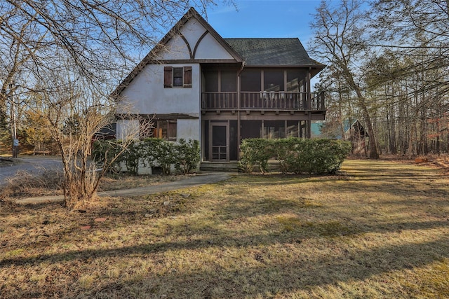 view of front of house featuring a front lawn, roof with shingles, and a sunroom