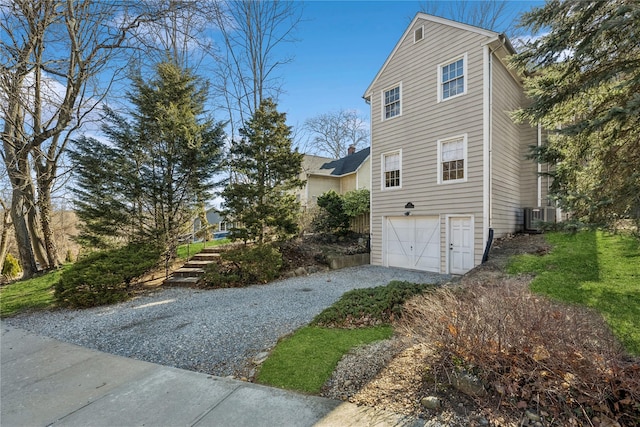 view of home's exterior featuring cooling unit, gravel driveway, and a garage