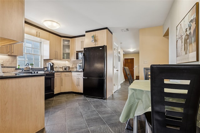 kitchen with dark countertops, visible vents, tasteful backsplash, light brown cabinets, and black appliances