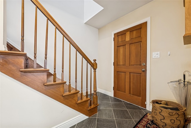 entrance foyer with baseboards, dark tile patterned floors, and stairs