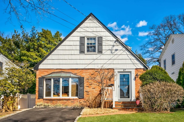 view of front of home featuring entry steps, fence, and brick siding