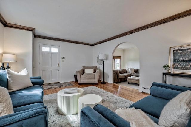 living room featuring arched walkways, baseboard heating, wood finished floors, and crown molding