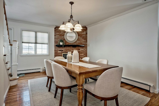 dining area featuring a baseboard heating unit, ornamental molding, and wood finished floors