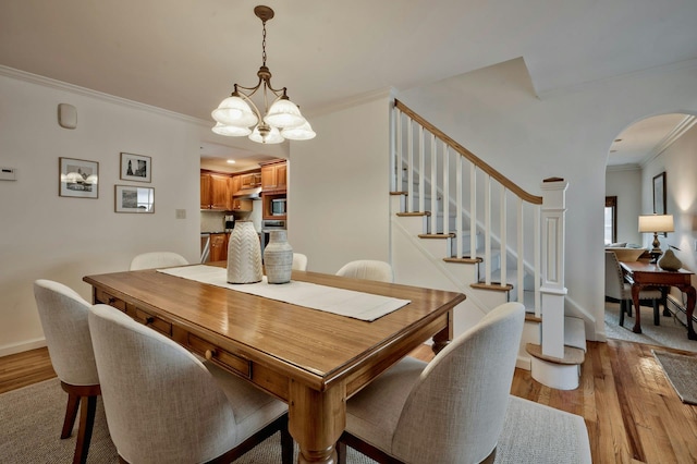 dining area with crown molding, stairway, light wood finished floors, and an inviting chandelier