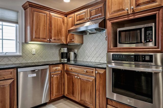 kitchen with stainless steel appliances, dark countertops, backsplash, and under cabinet range hood