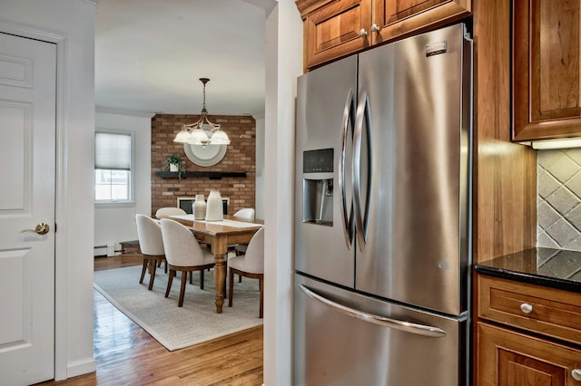 kitchen with decorative backsplash, ornamental molding, brown cabinets, light wood-style floors, and stainless steel refrigerator with ice dispenser