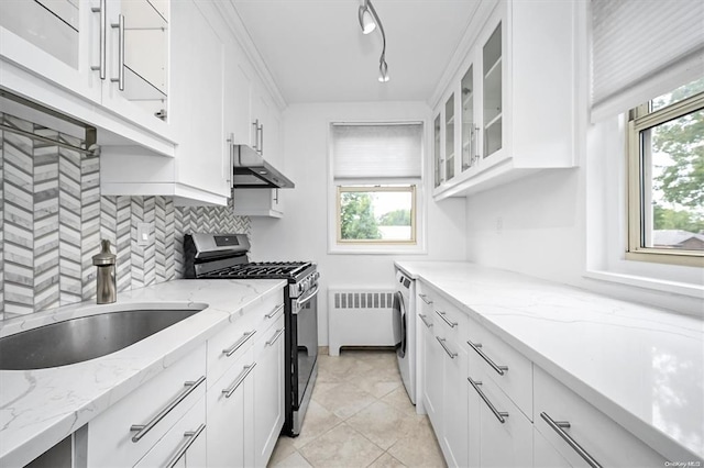 kitchen featuring radiator heating unit, glass insert cabinets, white cabinets, stainless steel gas stove, and under cabinet range hood