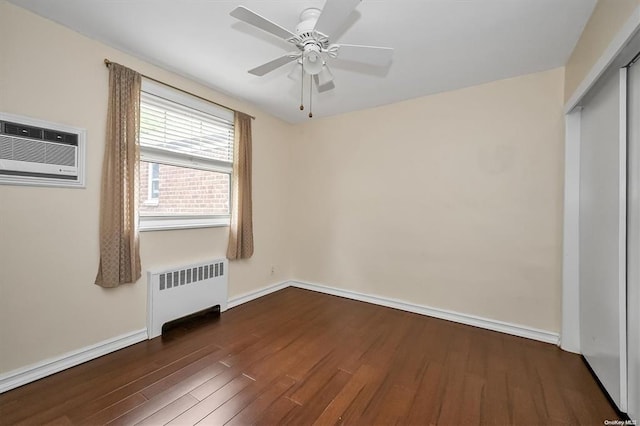 unfurnished bedroom with baseboards, a wall unit AC, radiator heating unit, dark wood-type flooring, and a closet