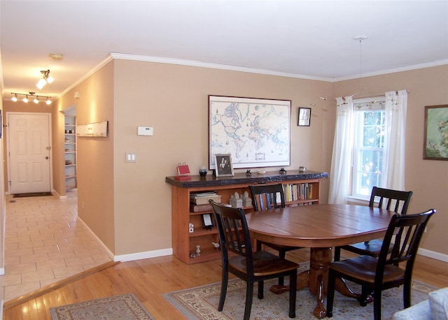 dining space with light wood-style flooring, baseboards, and crown molding