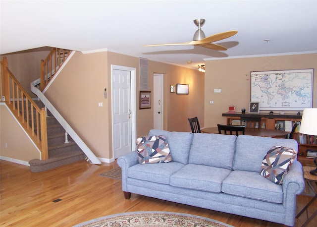 living area featuring light wood-type flooring, baseboards, stairway, and crown molding