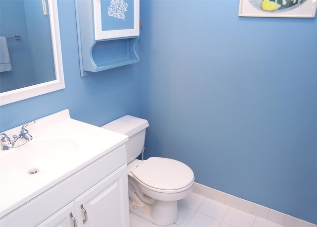 half bathroom featuring tile patterned flooring, baseboards, vanity, and toilet