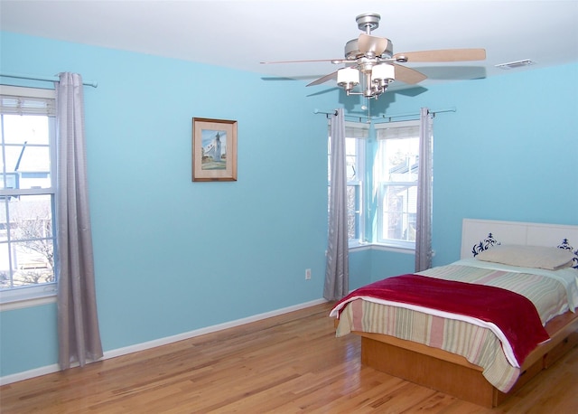 bedroom with light wood-style floors, multiple windows, and baseboards