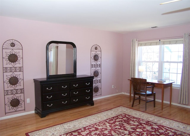 office space featuring light wood finished floors, visible vents, and baseboards