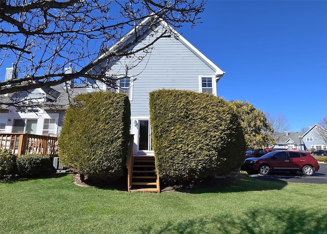 view of side of home featuring uncovered parking and a lawn