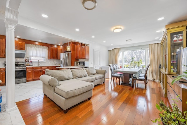 living room with light wood finished floors, recessed lighting, and ornate columns