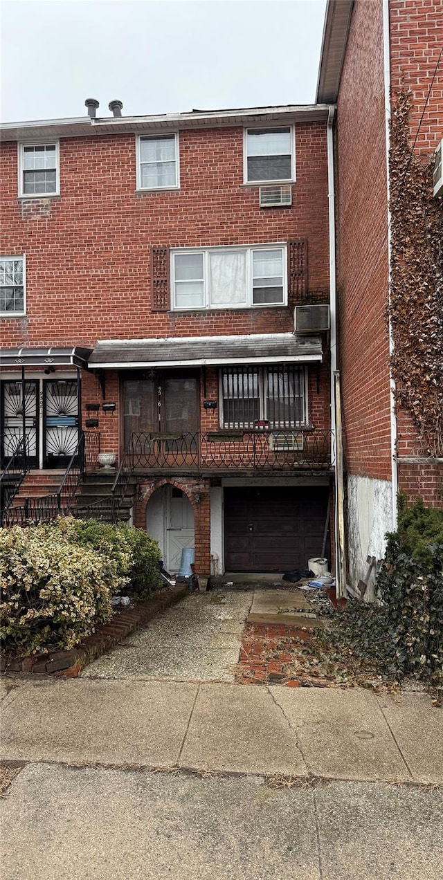 rear view of property featuring a garage, brick siding, and driveway