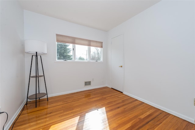 unfurnished room featuring light wood-style flooring, visible vents, and baseboards