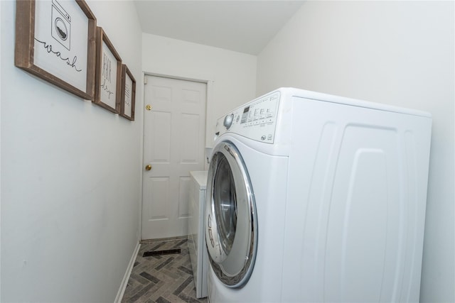 washroom featuring laundry area, baseboards, and washer / clothes dryer