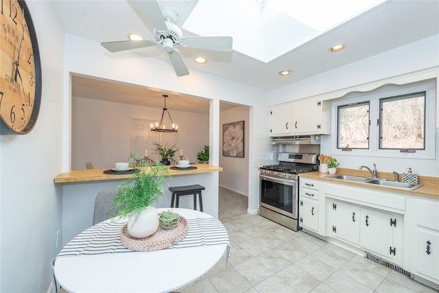 kitchen featuring stainless steel gas range oven, visible vents, light countertops, white cabinetry, and a sink