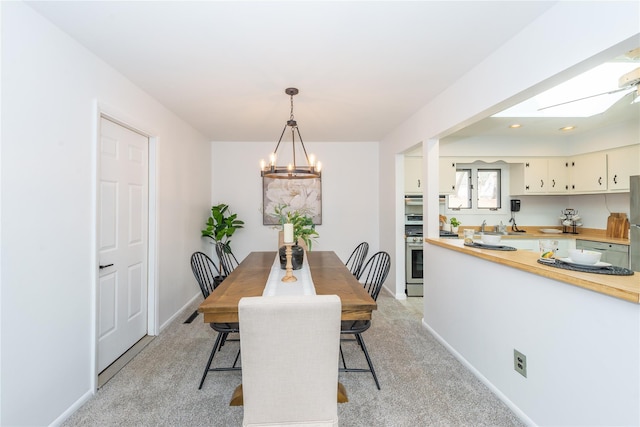 dining area with an inviting chandelier, baseboards, and light colored carpet