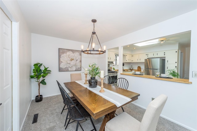 dining space with baseboards, ceiling fan with notable chandelier, visible vents, and light colored carpet