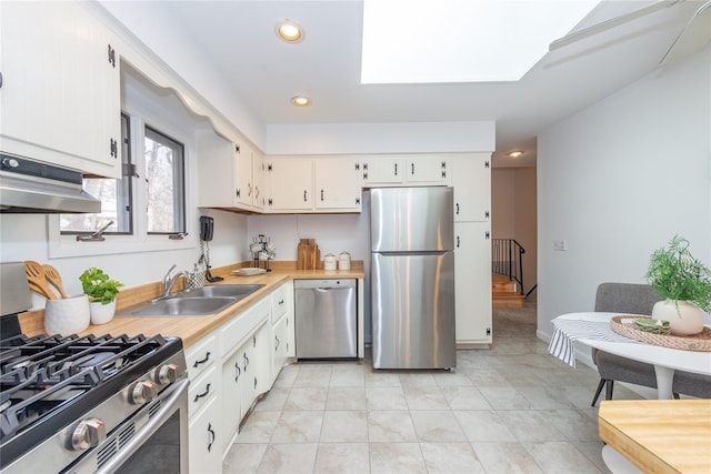 kitchen featuring stainless steel appliances, light countertops, under cabinet range hood, white cabinetry, and a sink