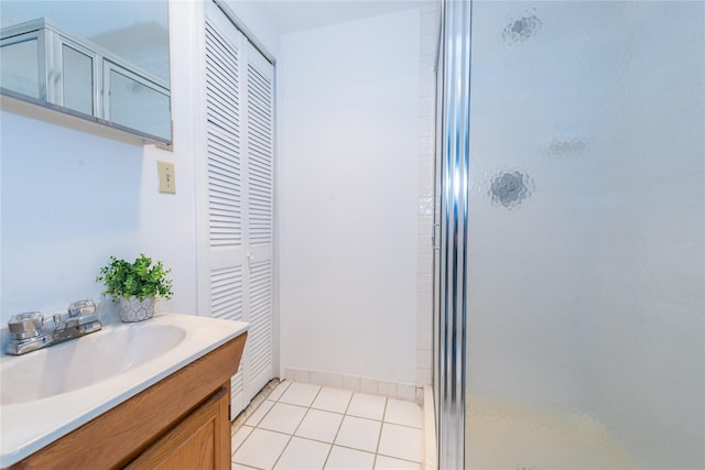 bathroom featuring baseboards, tile patterned flooring, vanity, a shower stall, and a closet