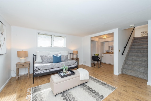 living room with light wood-style floors, visible vents, baseboards, and stairs