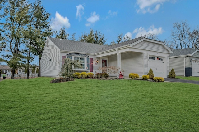 ranch-style home with driveway, a shingled roof, an attached garage, and a front yard