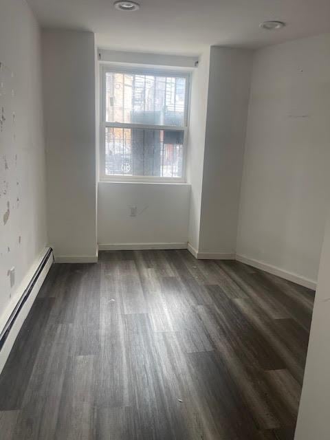 unfurnished room with wood finished floors, baseboards, and a baseboard radiator